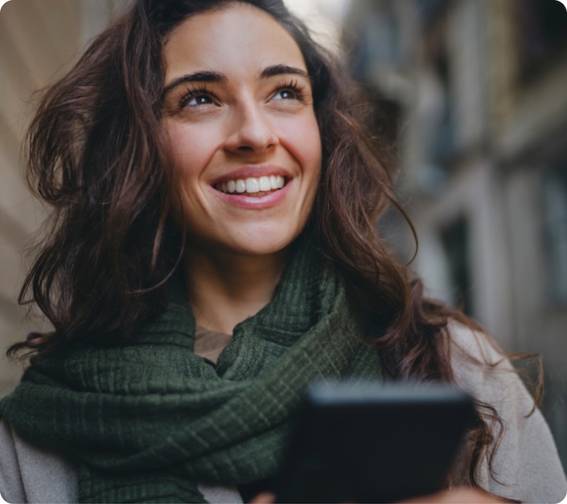 Fröhliche Frau mit Smartphone in der Hand.